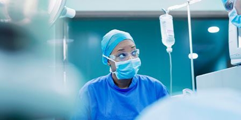 A female surgeon in scrubs is checking a screen