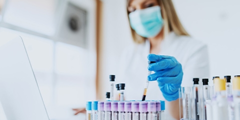 Woman with gloves and mask handles test tubes